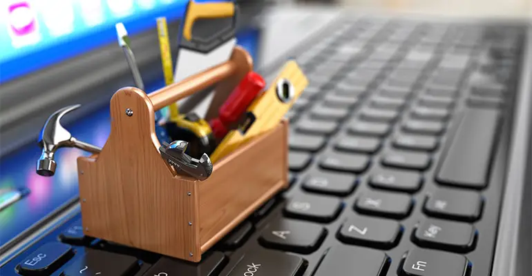 a small tool kit on top of the laptop illustrating web design maintenance